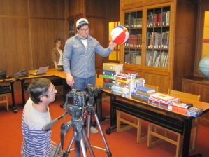 Prof. Steven Coy (left) and student Jared Patterson film the WorldShare sequence with librarian Gretchen Weiner looking on in the background.